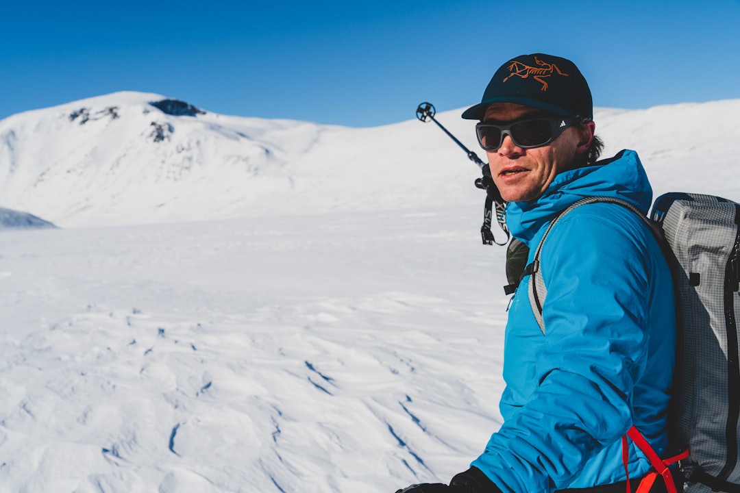 Skikjører peker på snødekt fjell