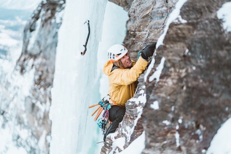 Mann som klatrer på stein og is