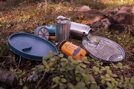 Biolite Campstove Complete Cook Kit består av kvistbrenner, vifte, batteri, ladekabel, lampe, vannkoker, presskannefilter og grillrist med lokk. Biolite Campstove Complete Cook Kit kvistbrenner med tilbehør i lyngen.