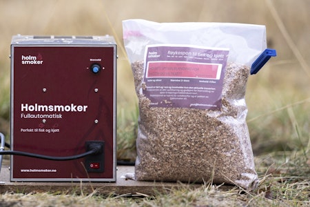 Røykovn: Holmsmoker røykgenerator med deres egenproduserte sponblanding til viltkjøtt. Det er viktig å ikke bruke for grov spon, for det tåler ikke fremdriftsskruen på Holmsmoker. Holmsmoker røykeovn med pose trespon ved siden av.