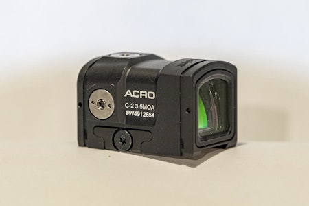 Med en lukket konstruksjon er Aimpoint Acro C2 litt annerledes enn de andre rødpunktsiktene i vår test. Aimpoint Acro C2 rødpunktsikte mot hvit bakgrunn.