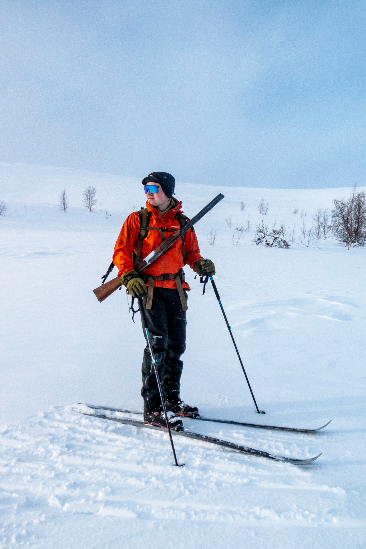 Jeger på vinterjakt med ski, hagle og Norrøna Falketind skalldress.