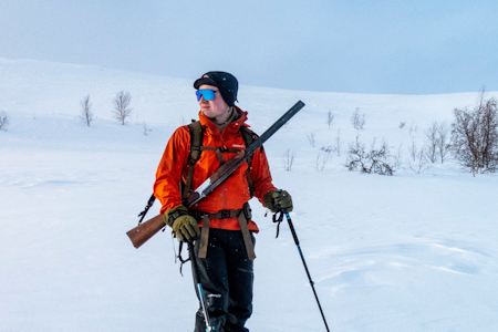 Jeger på vinterjakt med ski, hagle og Norrøna Falketind skalldress.