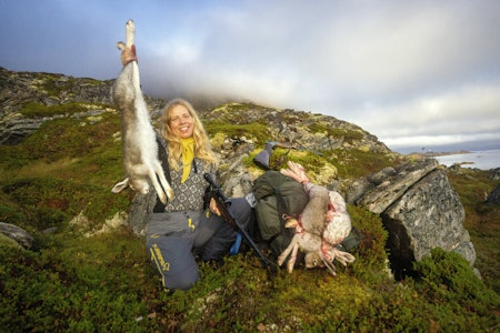 Jublende jeger: Elisabeth er stolt og glad, etter å ha felt sitt første vilt under toktet langs Finnmarkskysten. Kvinnelig jeger holder opp hare felt på støkkjakt.