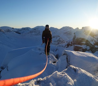 BRA ALTERNATIV: Når snøen er knallhard og skiføret elendig kan en klyvetur langs en smal rygg være et godt alternativ til å sitte hjemme i sofaen og sutre over dårlig skiføre. Foto: Tore Meirik mann med tau på fjellrygg i solnedgang