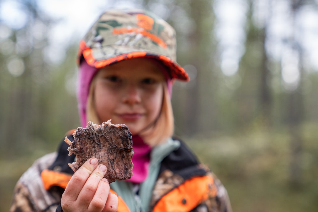 Kira Marie Slettås Håkonsson viser frem dagens lunsj: Dagsferskt elgkjøtt grillet på bålet. (Foto: Therese N. Andersen) Jente spiser elgkjøtt på skogstur