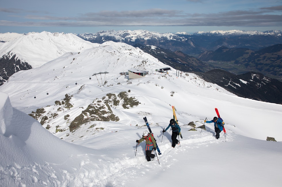 tre karer som går i fjellet med ski på sekken