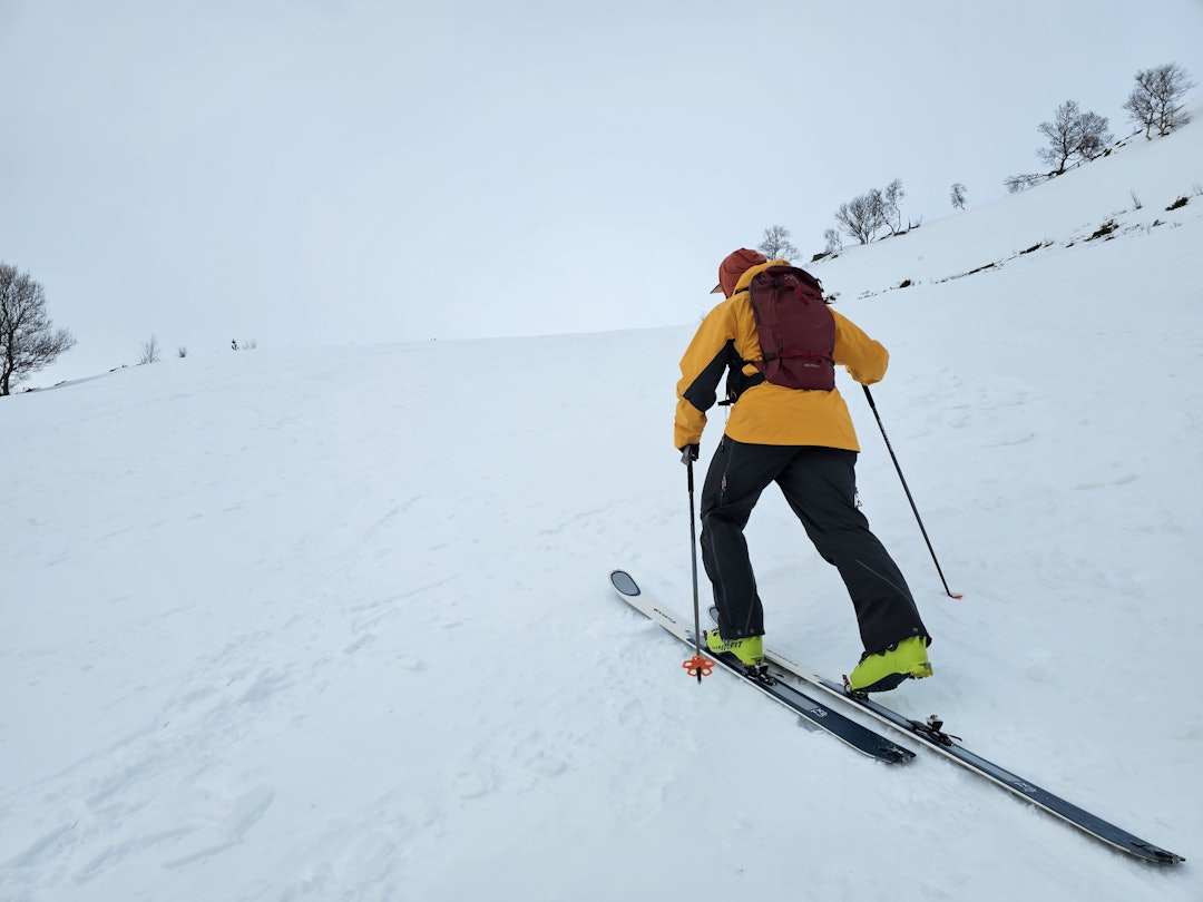 mann på vei opp med ski