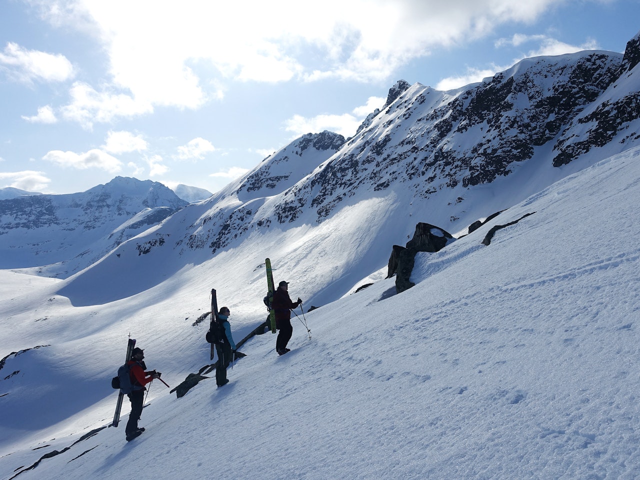 tre personer med ski på sekken på tur i vinterfjellet