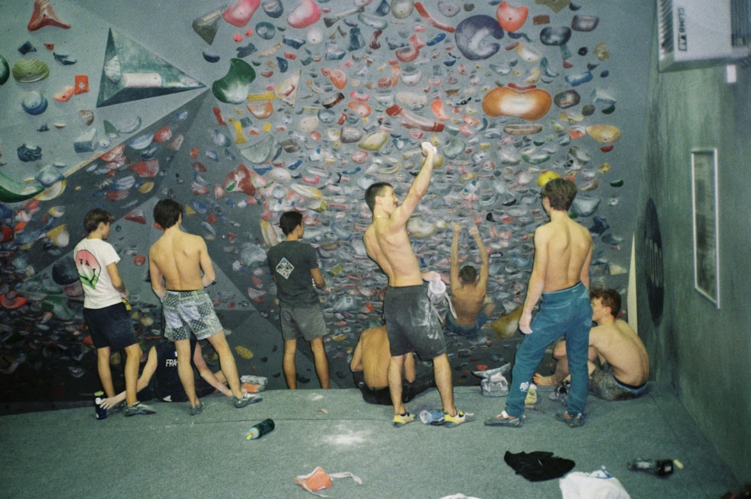 En gruppe ungdommer trener på en innendørs overhengende klatrevegg.