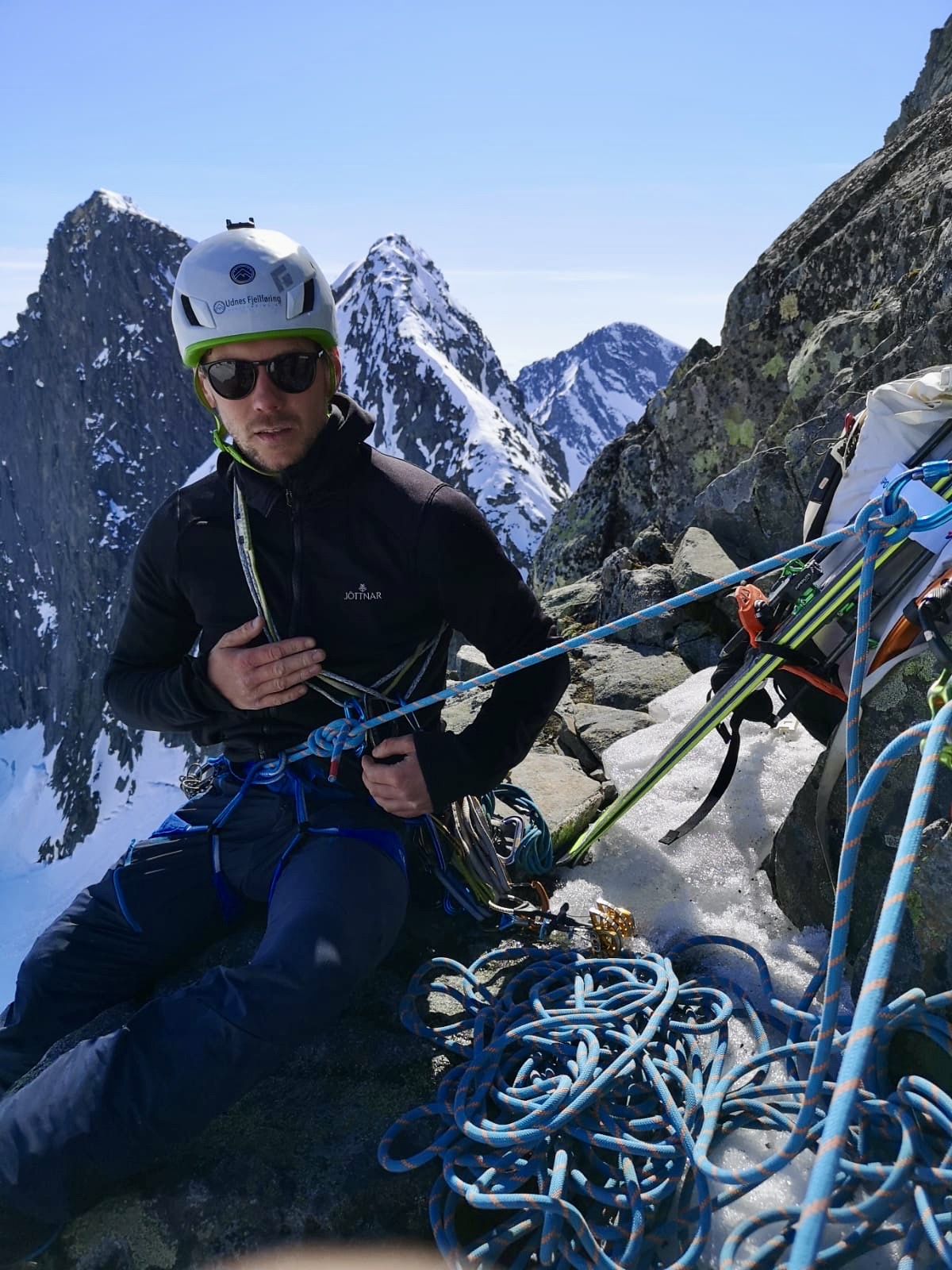klatrer på standplass med fjell i bakgrunnen
