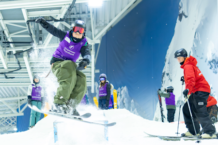 Skisenteret SNØ hadde 125 millioner kroner i underskudd i fjor. Foto: Achieved Media Alpinskikjører gjør et lite hopp på innendørs skisenter. Tre andre med ski på beina ser på