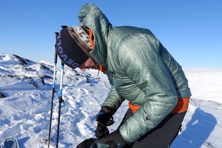 Tynne dunjakker har mange bruksområder, men det vanligste for toppturfolk er nok å varme seg på toppen. Foto: Siv-Elin Skogen Mann på vinterfjellet med grønn jakke