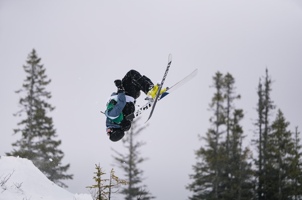 En mann med ski henger opp ned i luften
