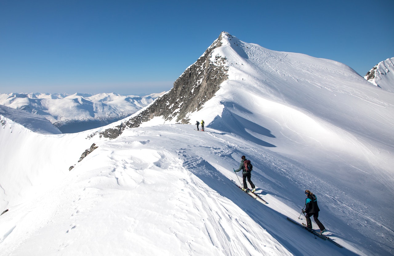 TRYGG KLASSIKER: Trolltinden på Nordmøre krever litt presisjon i vegvalgene, men den flotte toppen kan nås uten å ferdes i løsneområder for snøskred. Slik så det ut i midten av mars i år. Nora Skogen Fikse (12) og Siv-Elin Skogen nærmer seg toppen, og nyter utsikten mot fjellene i Romsdalen i bakgrunnen. Foto: Tore Meirik to skiløpere på vei mot fjelltopp