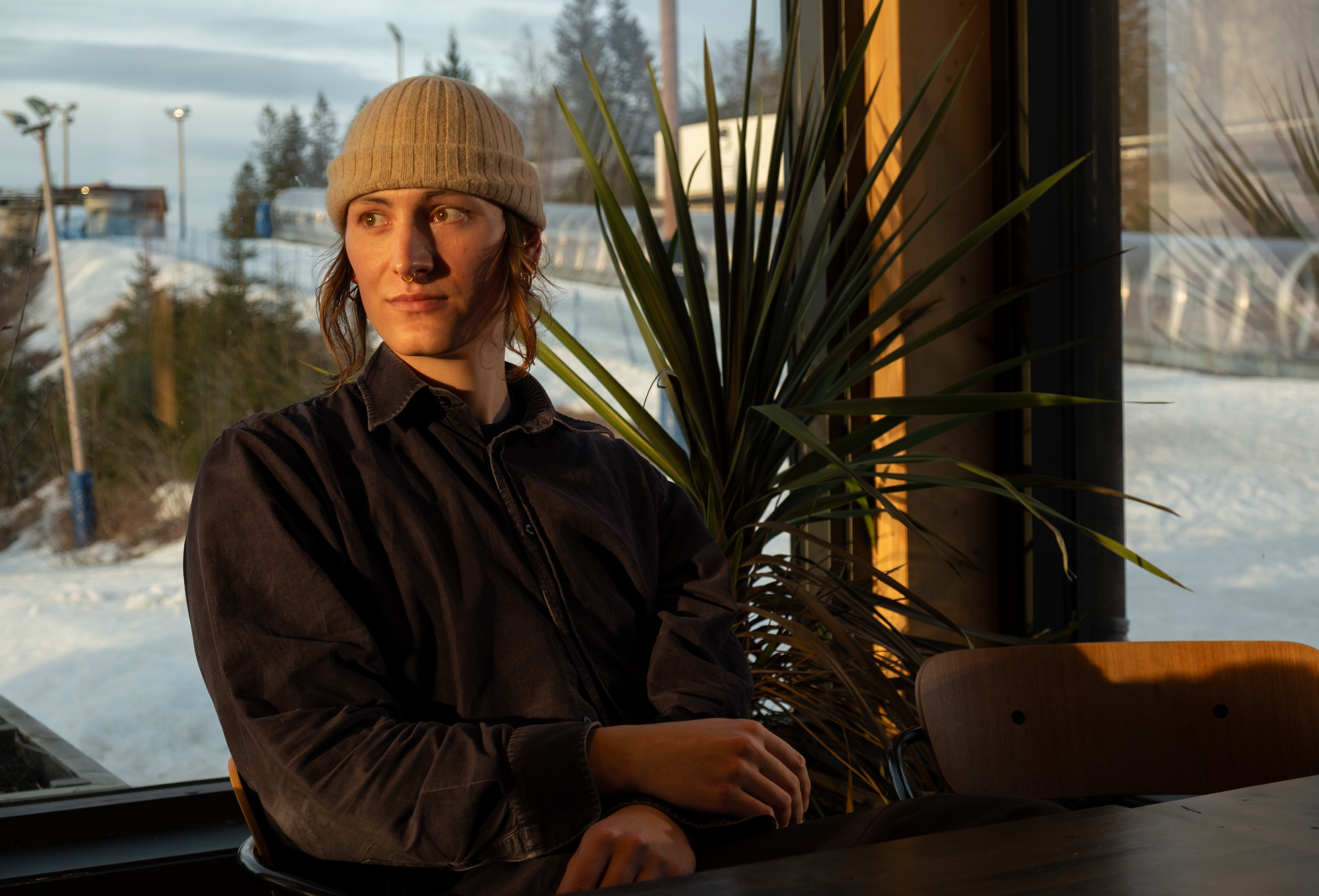 Kvinne med hvit lue som sitter i en stol og ser ut i luften.