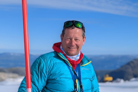 ILDSJEL Den tyske alpinttreneren Thomas Burda er en av ildsjelene som vil blåse liv i Fonna. Foto: Privat mann i vinterklær på fjellet i solrik dag, anleggsmaskin i bakgrunnen