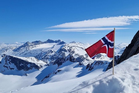 TOPPTUR PÅ NASJONALDAGEN: Lørdag må du stålsette deg for bilder av folk på skitur med både bunad og flagg. Dette er en regobs fra Ofoten på nasjonaldagen i 2024. Foto: turid@nve/regobs norsk flagg i snøkledde fjell