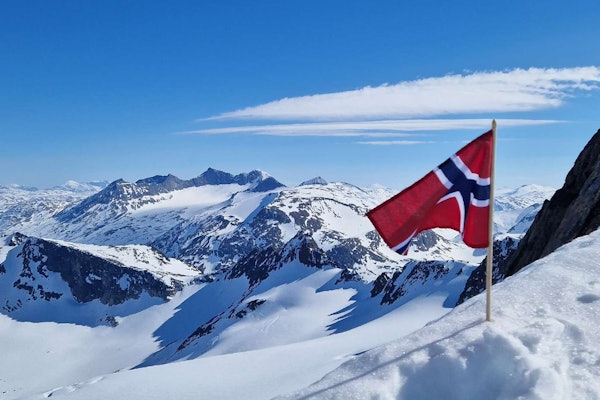 TOPPTUR PÅ NASJONALDAGEN: Lørdag må du stålsette deg for bilder av folk på skitur med både bunad og flagg. Dette er en regobs fra Ofoten på nasjonaldagen i 2024. Foto: turid@nve/regobs norsk flagg i snøkledde fjell