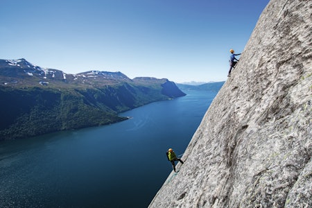 NORGES LENGSTE: Ikke mange steder i verden kan du klatre nesten 700 meter på borebolter i så nydelige omgivelser som dette. Her er Miroslav Pet´o først i tauet på Balansekoden (7-) i Eresfjord, sikret av legenden Iver Gjelstenli. Foto: Terje Aamodt to klatrere i fjellvegg med fjord i bakgrunnen