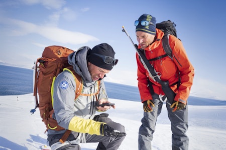 MER HENSYN: Rifle og signalpistol er like obligatorisk som skredsøker på Svalbard-tur. Foto: Kristin Folsland Olsen / Toppturfestivalen Svalbard To guider på svalbard diskuterer rutevalg den ene med rifle på ryggen