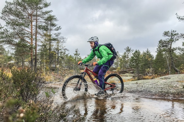 NATURLIG HABITAT: Sykkelen har tatt meg med på mange eventyr, som her i området rundt Canvas Telemark i Nissedal. Foto: Krister Sørbø Syklist på stisykkel sykler gjennom vann ved Canvas i Telemark.