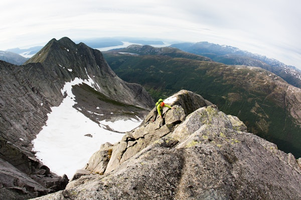 UTSIKT: Brendan Leonard på Kolkjerreryggen (4) i Uskedalen, en ryggtravers opp nordøstryggen på Akslo. Foto: Forest Woodward mann klyver oppover ryggtravers med utsikt over fjord og fjell i bakgrunn