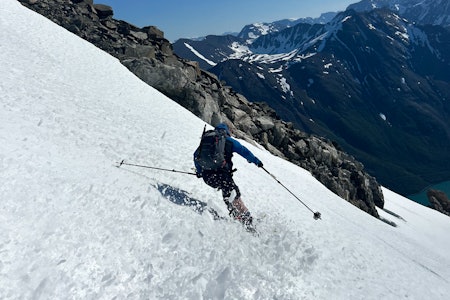 SOMMERSNØ: Store Kjostinden har flust av god snø som er leken og trygg i juli. Foto: Torben Rognmo. En mann med blå jakke kjører ned Store Kjostinden.
