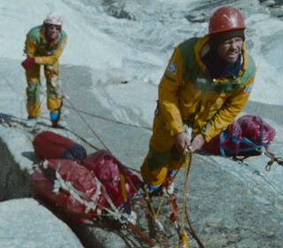 UNIK DOKUMENTASJON: Klipp fra den banebrytende klatringen i Pakistan, vises for første gang i kinofilmen Trango. To menn står i en klatrevegg med gule jakker og kikker oppover