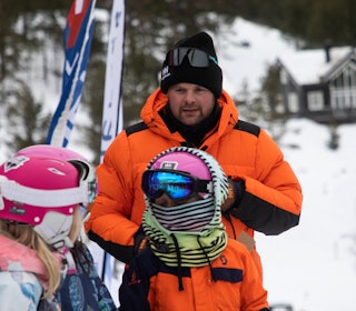 Hans Petter Bakke er imponert og overrasket over giverviljen når folk i Gudbrandsdalen samler inn penger for å redde skisenteret på Lemonsjøen. mann i oransje dunjakke foran kids
