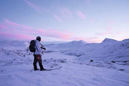 PÅ VINTERJAKT ETTER RYPE: Godt kledd jeger i vinterfjellet med ski, sekk og rifle vinterjakt rype