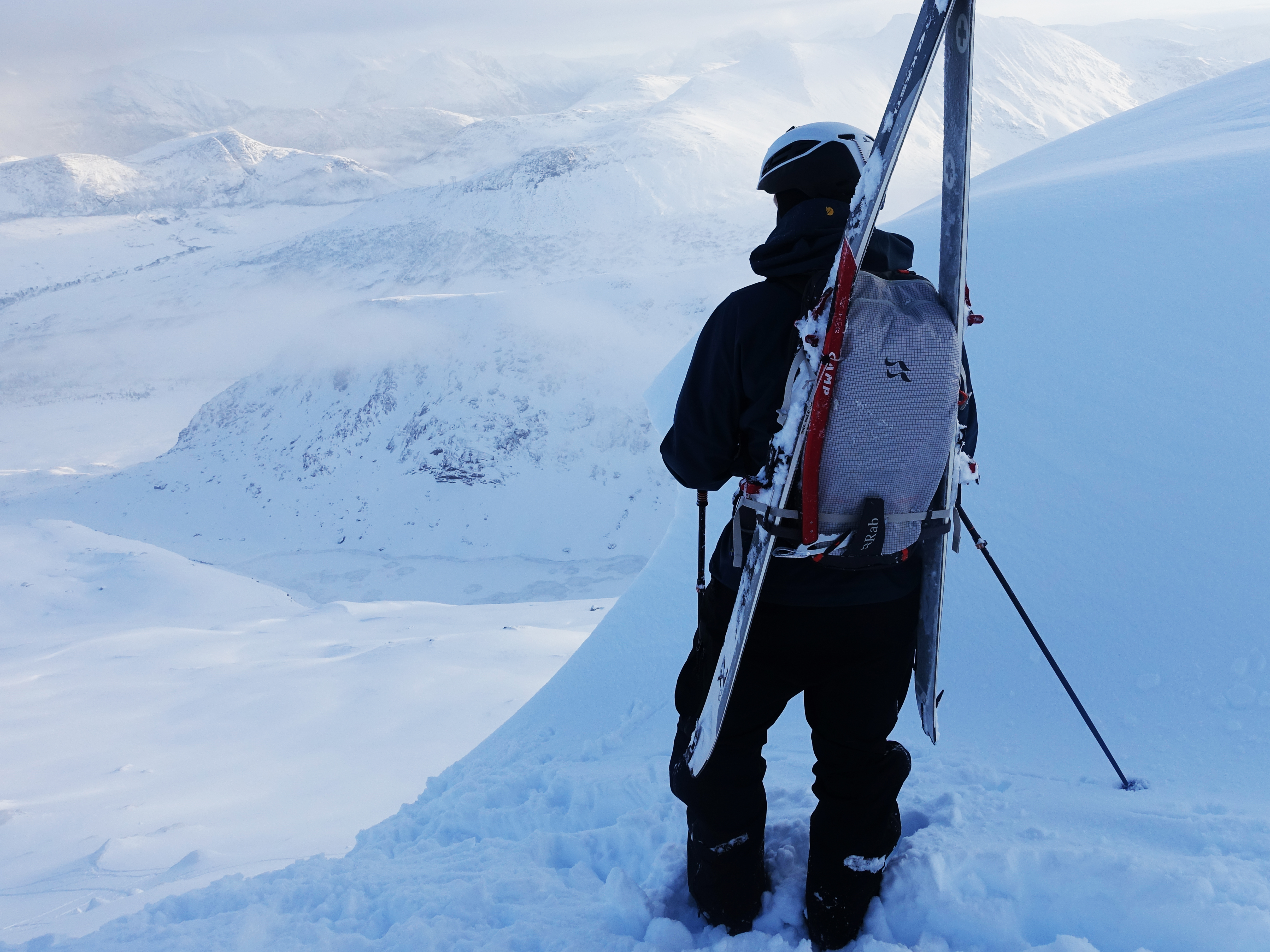 mann som ser på utsikten med ski på sekken