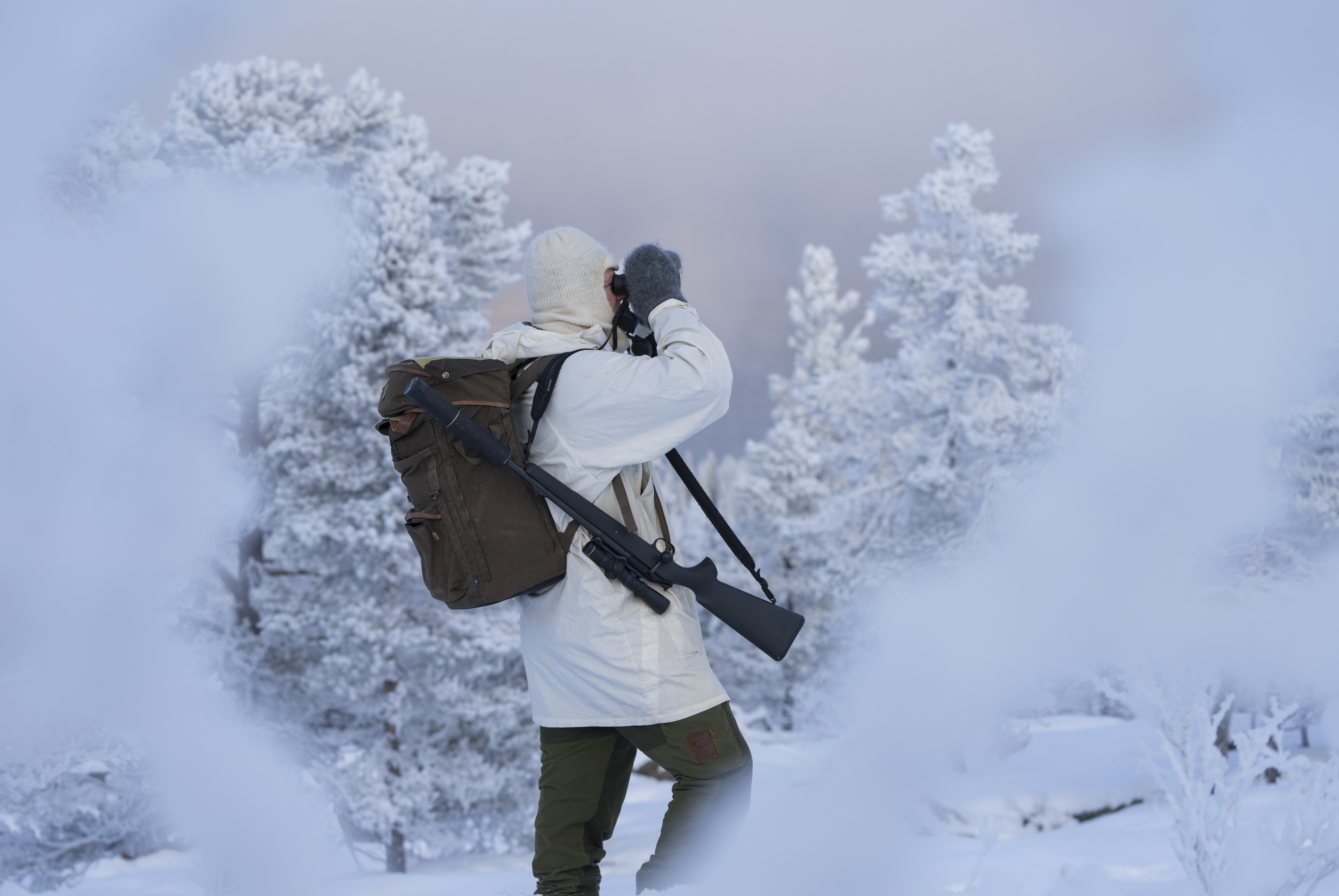 Jeger med kikkert i vinterlandskap