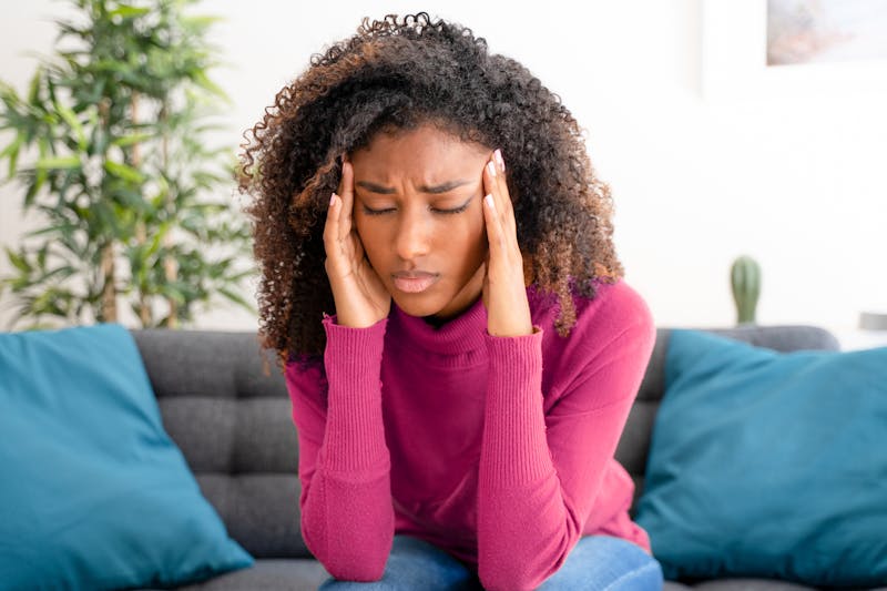 woman sitting on a couch with her hands on her head