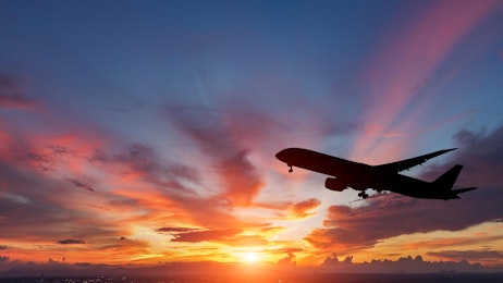 Vliegtuig dat door de lucht vliegt bij zonsondergang