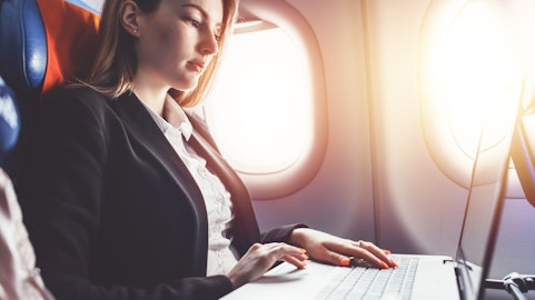 Een vrouw die aan een laptop werkt in een vliegtuig