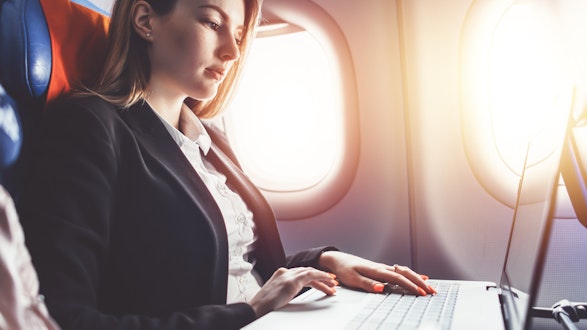 A woman working on a laptop on a plane