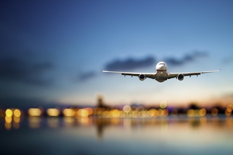 Flugzeug fliegt in der Abenddämmerung über Wasser