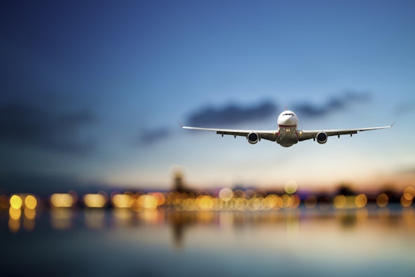 Flugzeug fliegt in der Abenddämmerung über Wasser