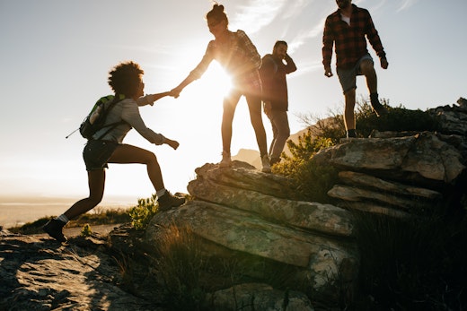 Group of travellers helping each other on hike