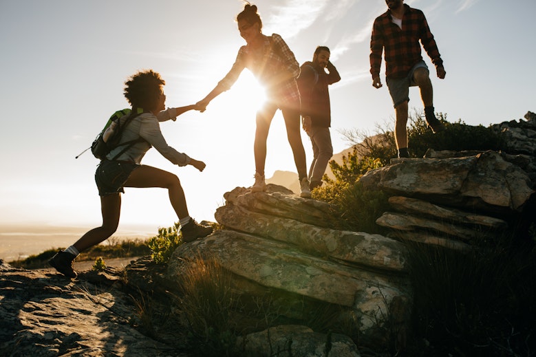 Gruppe von Reisenden, die sich gegenseitig beim Wandern helfen