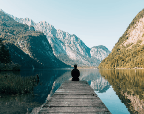 Traveller sitting by lake and mountains
