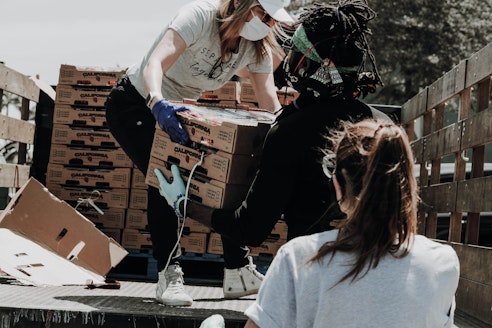 Two women and a man taking boxes of food off a truck on a catholic mission trip