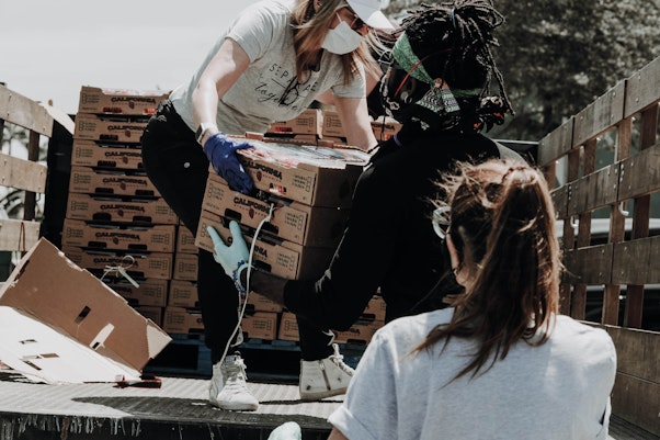 Deux femmes et un homme prenant des boîtes de nourriture d'un camion lors d'un voyage de mission catholique