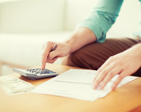 Man calculating budgets with money, paperwork and calculator