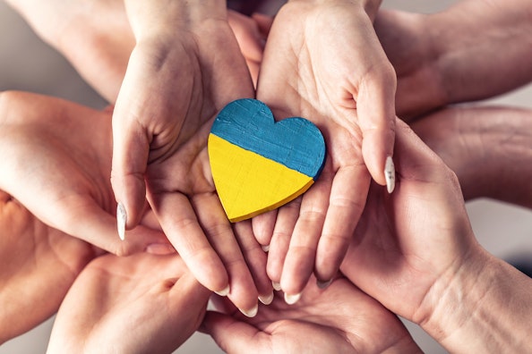 Un groupe de mains tenant un cœur en bois peint avec le drapeau ukrainien