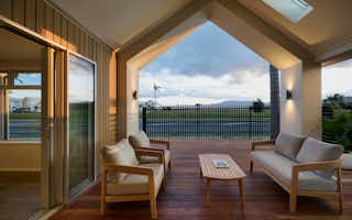 Outdoor living area in New Zealand home with timber deck, modern gable roof, and alfresco seating for year-round entertaining
