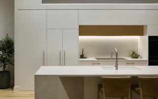 White and light timber kitchen design with hidden fridge and scullery