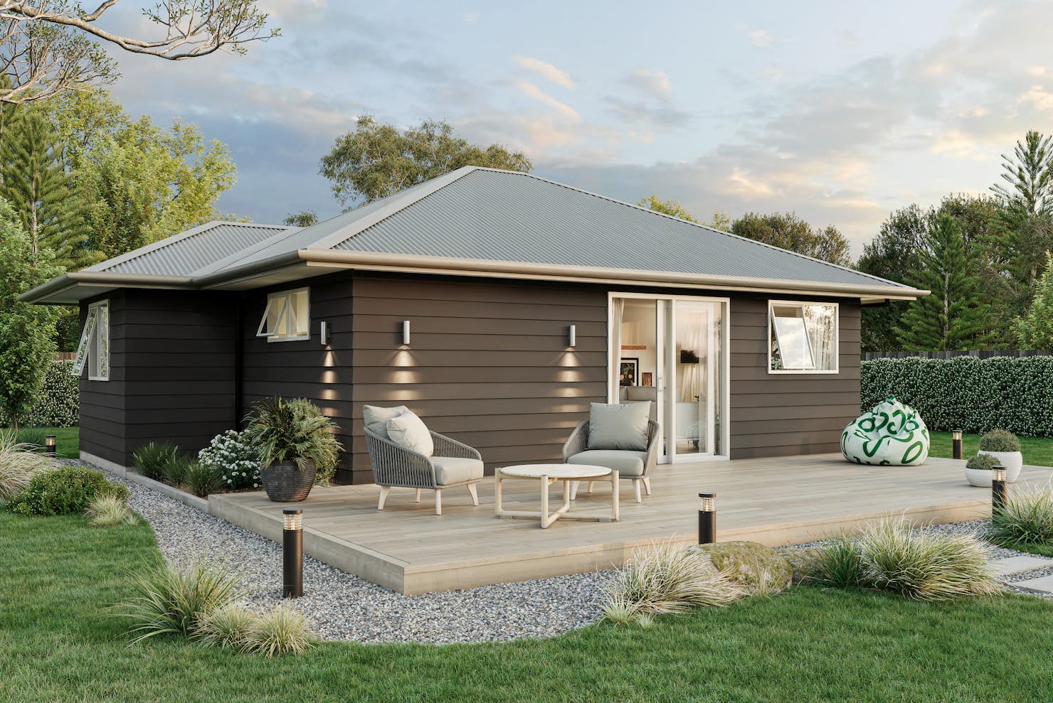 Two-bedroom minor dwelling exterior with timber deck, dark weatherboard cladding, and outdoor seating, designed by Signature Homes.