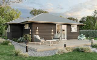 Two-bedroom minor dwelling exterior with timber deck, dark weatherboard cladding, and outdoor seating, designed by Signature Homes.